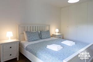 a bedroom with a bed with two lamps and towels at The North House by Ponta Negra Azores in Biscoitos