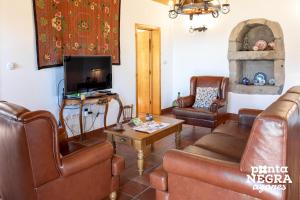a living room with leather furniture and a tv at Casa da Hortênsia Roxa by Ponta Negra Azores in Praia da Vitória