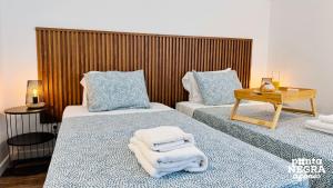 two beds in a room with towels on them at The Biscuit House by PontaNegraAzores in Praia da Vitória