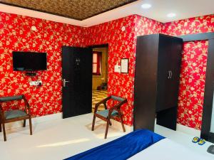 a bedroom with red walls and two chairs and a tv at Hostel stay bless in Jaisalmer