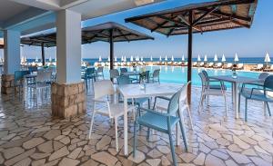 a restaurant with tables and chairs with the ocean in the background at Radisson Resort Ruza Vjetrova in Dobra Voda