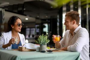 a man and woman sitting at a table with drinks at Andaman Riviera in Bang Tao Beach