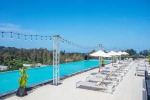 a pool at a resort with lounge chairs and umbrellas at Andaman Riviera in Bang Tao Beach