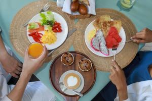 a group of people sitting at a table with breakfast foods at Andaman Riviera in Bang Tao Beach