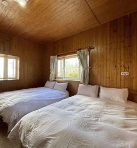 two beds in a room with wooden walls at Xiayun in Fuxing