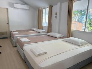 three beds in a room with a window at Tharnvara Resort in Ban Khok Sung