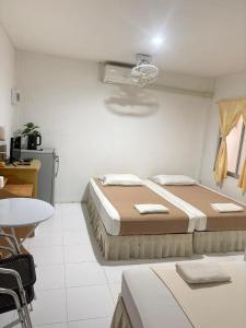 a bedroom with two beds and a table and a desk at Tharnvara Resort in Ban Khok Sung