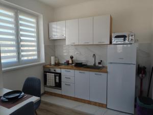 a kitchen with white cabinets and a white refrigerator at Studio Apartman Tara in Daruvar