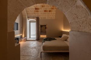 a bedroom with a bed in a room with an archway at Palazzo Cerere Boutique Hotel in Polignano a Mare