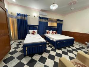 two beds in a room with a checkered floor at Rose Family Lodges in Islamabad
