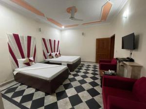 a room with two beds and a couch and a tv at Rose Family Lodges in Islamabad