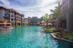 a pool at a resort with palm trees and buildings at Mai Holiday by Mai Khaolak - Adult Zone in Khao Lak