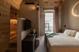 a bedroom with a bed and a tv on a wall at Palazzo Cerere Boutique Hotel in Polignano a Mare