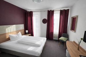 pokój hotelowy z białym łóżkiem i czerwonymi zasłonami w obiekcie Hotel Brigach w mieście Villingen-Schwenningen