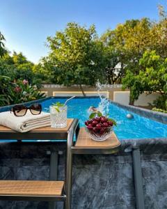 a table with glasses and a bowl of fruit next to a swimming pool at Privé Residence in Rāmnagar