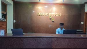 a man sitting at a desk with two laptops at Hotel Tamilnadu Trichy in Tiruchirappalli