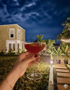 a person holding a drink in front of a house at Privé Residence in Rāmnagar