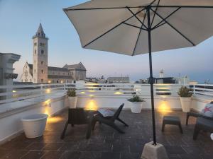 a patio with chairs and an umbrella on a roof at White House in Trani