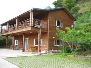 a wooden house with a balcony and a patio at Xiayun in Fuxing