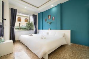 a bedroom with a large white bed with blue walls at Gia Khanh Hotel in Da Lat