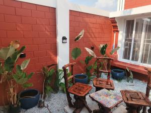 a patio with chairs and plants next to a red wall at Amaiti pool villa in Bangalore