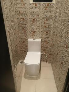 a white toilet in a bathroom with a tile wall at Amaiti pool villa in Bangalore