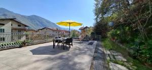a table with a yellow umbrella on a patio at Appartamento Caffaro Vacanza in Ponte Caffaro