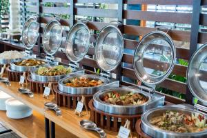 a buffet line of food in metal trays at Almont Inland Resort in Butuan