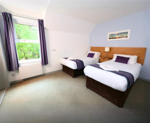 a hotel room with two beds and a window at The Caledonian Claymore Hotel in Arrochar