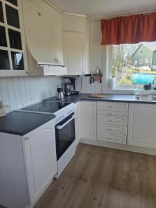 a kitchen with white cabinets and black counter tops at Cabin in Leirvåg in Leirvåg