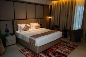 a bedroom with a large bed with white sheets and pillows at La Belle - The Business Hotel in Lubumbashi
