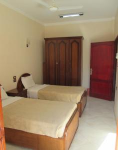 a hotel room with two beds and a cabinet at Fayrouz Apartmernts in Luxor