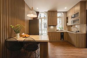 a kitchen with wooden cabinets and a table with chairs at Amy Apartment Hue in Hue