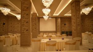 a banquet hall with tables and chairs and chandeliers at Hotel Roma Kristo in Dwarka