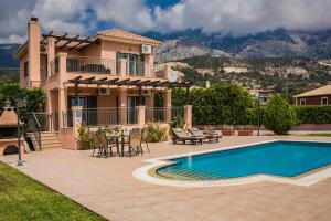 a villa with a swimming pool in front of a house at Athina Rose in Trapezaki