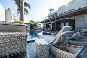 a group of wicker chairs and a table next to a pool at sul mare סוויטות in Ashkelon