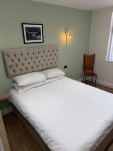 a large white bed in a room with a chair at west park hotel PVT ltd in Clydebank +11 photos