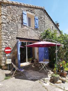 a house with a table and an umbrella in front of it at à 10 mn des Gorges de l'Ardèche in Bidon