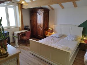 a bedroom with a large white bed and a wooden cabinet at à 10 mn des Gorges de l'Ardèche in Bidon
