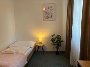 a room with two beds and a table with a lamp at Garni G Hotel Žilina in Žilina