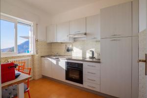 a kitchen with white appliances and a table and a window at Al Pianaccio by Lago Reisen in Trarego Viggiona