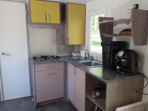 a small kitchen with yellow cabinets and a sink at Mobil-home Moon River in Thiviers
