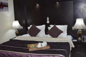 um quarto de hotel com uma cama com uma bandeja de comida em cima em Citiheight Hotel em Ikeja