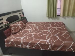 a bedroom with a bed with a brown and white comforter at Shri Shyama seva kunj in Vrindāvan +5 photos