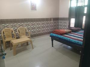 a room with two chairs and a bed and a bench at Shri Shyama seva kunj in Vrindāvan