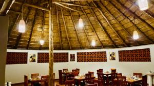 a dining room with tables and chairs and a large ceiling at Ewafe Safari Lodge-Murchison in Wanseko