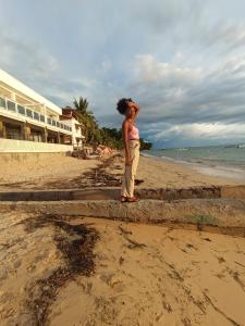 a girl standing on the beach near the ocean at Bee Rooms Nosy be in Ambatoloaka