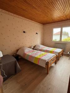 a bedroom with two beds and a table in it at Maison chaleureuse de village - location logement entier in Lanans
