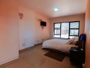 a bedroom with a bed and a tv on the wall at Grand View B&B in Johannesburg