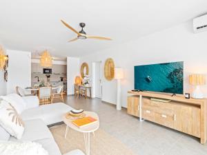 a living room with a white couch and a large screen tv at Ocean Breeze, Fully Renovated Beachfront 2 bdr in Baie Nettle